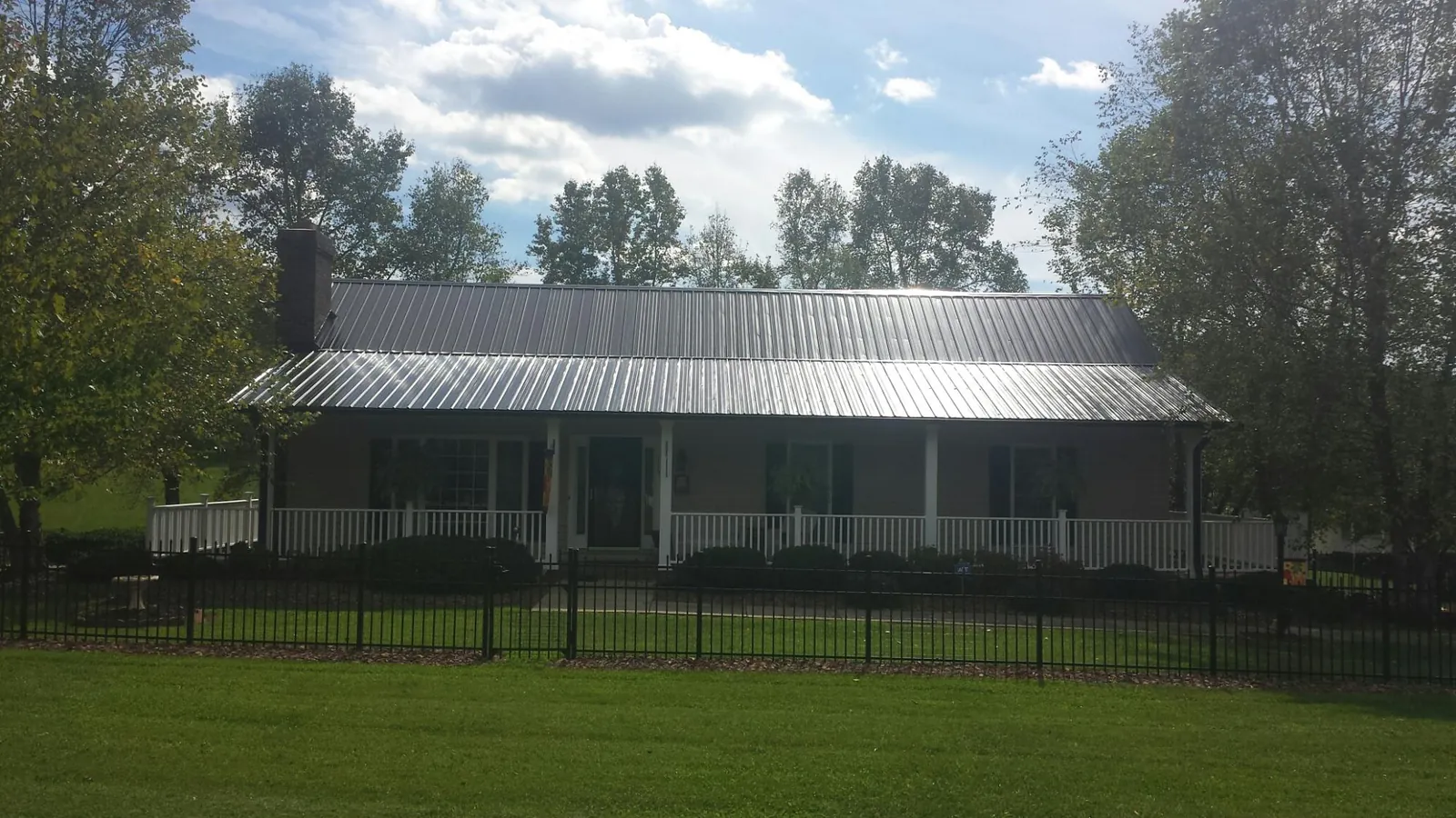 Gray metal roof on a brick ranch with a full width front porch — Gutter Guard Installation work by our crew in Highlands