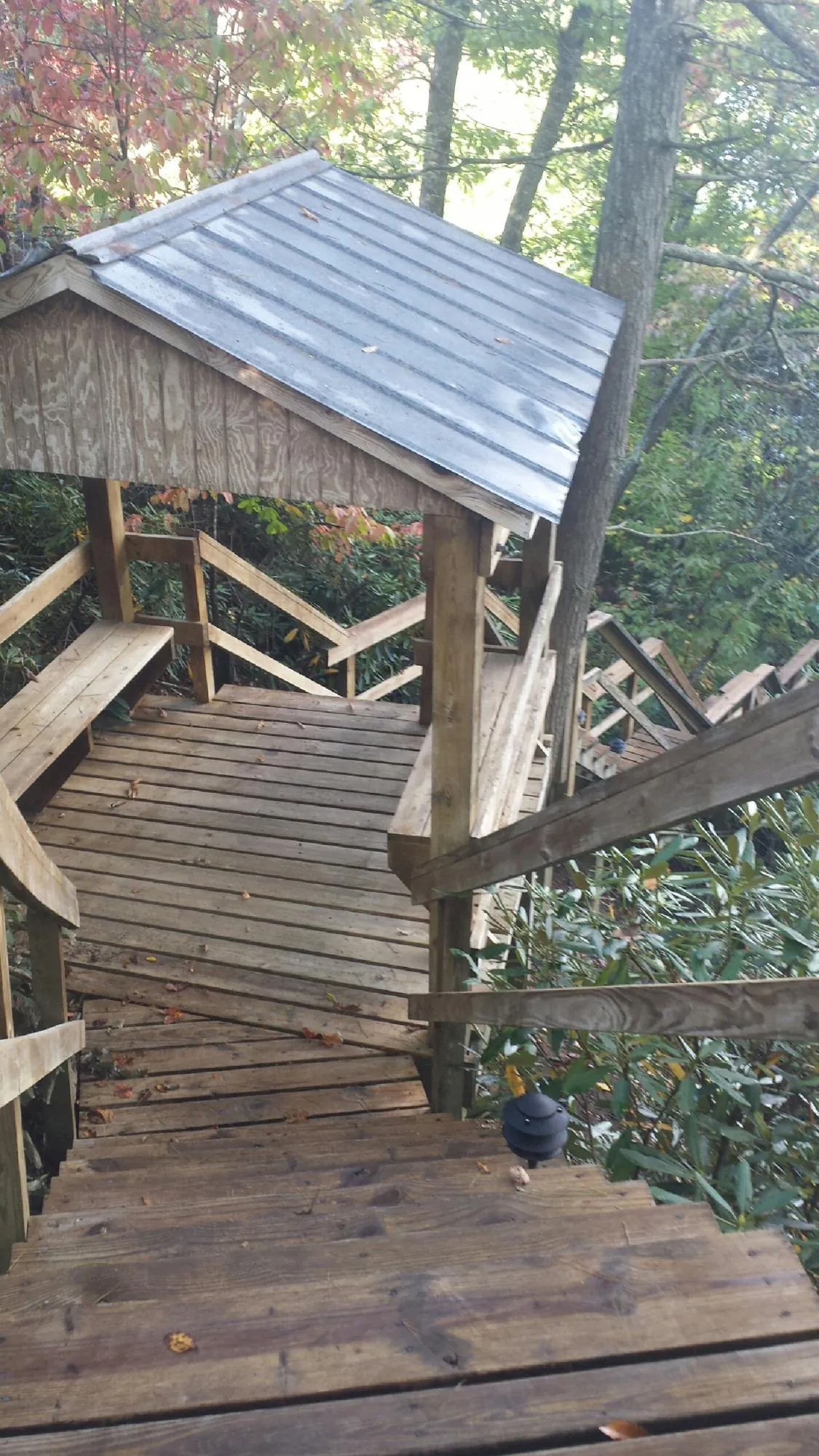 Metal roofed shelter over wooden steps on a wooded walkway — Skylight Repair & Installation work by our crew in Highlands